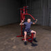 White male athlete performing seated shoulder press with a slight lean forward on the Best Fitness by Body-Solid Single Stack Home Gym BFMG30.