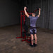 White male athlete performing standing shoulder press using the Best Fitness by Body-Solid Single Stack Home Gym BFMG30.