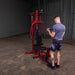 White male athlete performing standing bicep curl with low row short straight handle cable attachment on the Best Fitness by Body-Solid Single Stack Home Gym BFMG30.