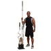 Athlete standing next to the Body-Solid GOBH5 Olympic Bar Holder 5 Bar Vertical storage rack in a gym setting, showcasing organized barbell storage.