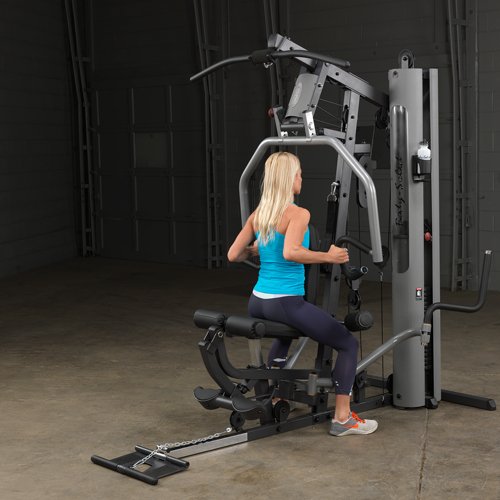 Female athlete seated and performing a row on Body-Solid G5S Home Gym, pulling handles toward her torso.