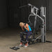 Female athlete doing an ab crunch on Body-Solid G5S Home Gym, pulling cable down from overhead.