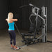 Female athlete completing upright cable row on Body-Solid G5S Home Gym with elbows fully raised.