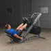 Athlete performing a fully extended leg press on the Body Solid Angled Leg Press & Hack Squat Machine, legs fully extended, demonstrating lower body strength exercise.