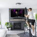 Male using the VersaClimber Home Climber with a live square display, engaging in a high-intensity vertical cardio workout with real-time metrics and guided on-demand fitness classes shown on the built-in tablet screen in his livingroom
