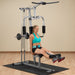 White female athlete in a teal top performing leg extension on the Powerline Home Gym PHG1000X."