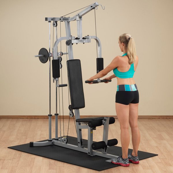White female athlete in a teal top performing standing shoulder press down from the low row cable on Powerline Home Gym PHG1000X.