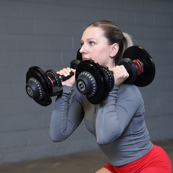 Person holding Body-Solid Tools SDBX132 Adjustable Dumbbells performing squats with a neutral grip at shoulder height.