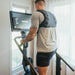 Male athlete working out on the STEPR+ Stair Climber at home, backside view, showing the compact design fitting easily into a residential space.