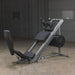 Body Solid Angled Leg Press & Hack Squat Machine side view in a warehouse setting, showcasing the quad track roller system, diamond plate foot platforms, and heavy-duty frame for leg press and hack squat exercises.