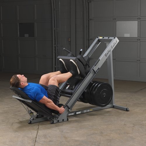 Athlete in starting leg press position on the Body Solid Angled Leg Press & Hack Squat Machine, knees bent and feet positioned on the foot platform, preparing for a leg press exercise.