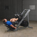 Athlete in starting leg press position on the Body Solid Angled Leg Press & Hack Squat Machine, knees bent and feet positioned on the foot platform, preparing for a leg press exercise.