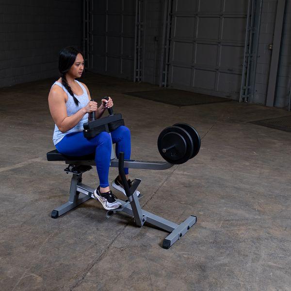 Female athlete working out on the Body-Solid GSCR349B Seated Calf Raise Machine with black weight plates, demonstrating proper use and form.