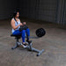 Female athlete working out on the Body-Solid GSCR349B Seated Calf Raise Machine with black weight plates, demonstrating proper use and form.