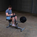 Male athlete working out on the Body-Solid GSCR349B Seated Calf Raise Machine with black weight plates, demonstrating proper use and form.