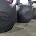 Close-up of heavy ISF kettlebells on the warehouse floor, viewed from the left side looking right.