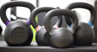 Close-up of four ISF kettlebells on a flat weight bench.