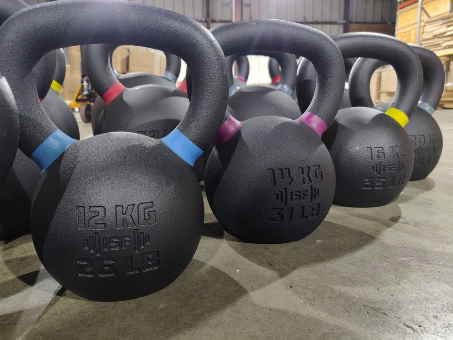Close-up of ISF kettlebells on the warehouse floor, viewed from the left side looking right.
