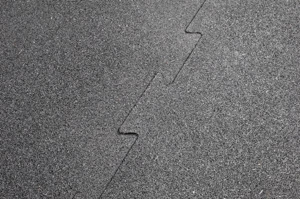 Close-up of interlocking black puzzle mats where they interlock made of heavy-duty rubber, showcasing the puzzle-style edges for easy installation, designed to protect floors and equipment in any workout space.