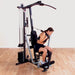Female athlete performing an ab crunch with the included strap on a Body-Solid G1S Multi-Station Home Gym, targeting core muscles for enhanced abdominal strength.