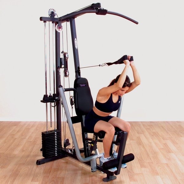 Female athlete performing a seated overhead tricep extension with the included strap on a Body-Solid G1S Multi-Station Home Gym, targeting tricep muscles for upper arm strength.