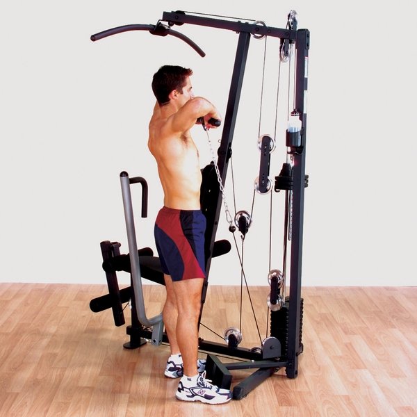 Male athlete performing a shoulder row with the included short straight bar cable attachment on a Body-Solid G1S Multi-Station Home Gym, targeting back and shoulder muscles for upper body strength.