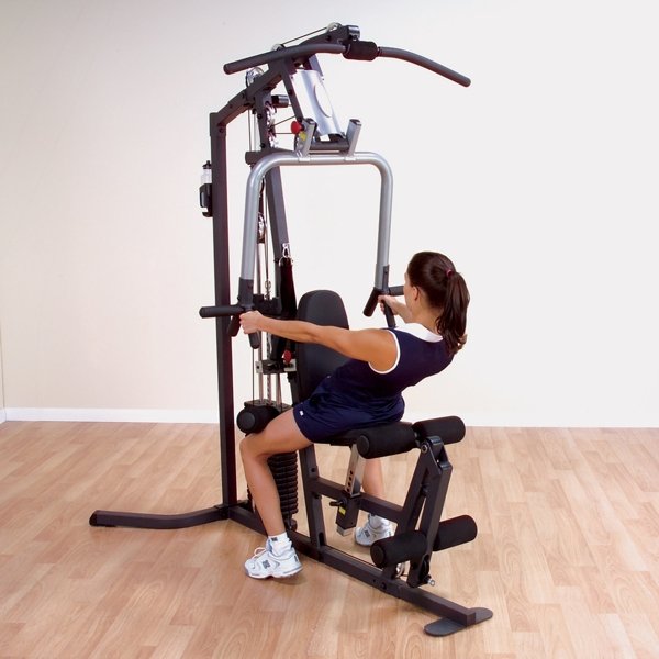 White female athlete performing rows on the Body Solid Home Gym G3S with angled back, using the mid-row handles for a back workout.